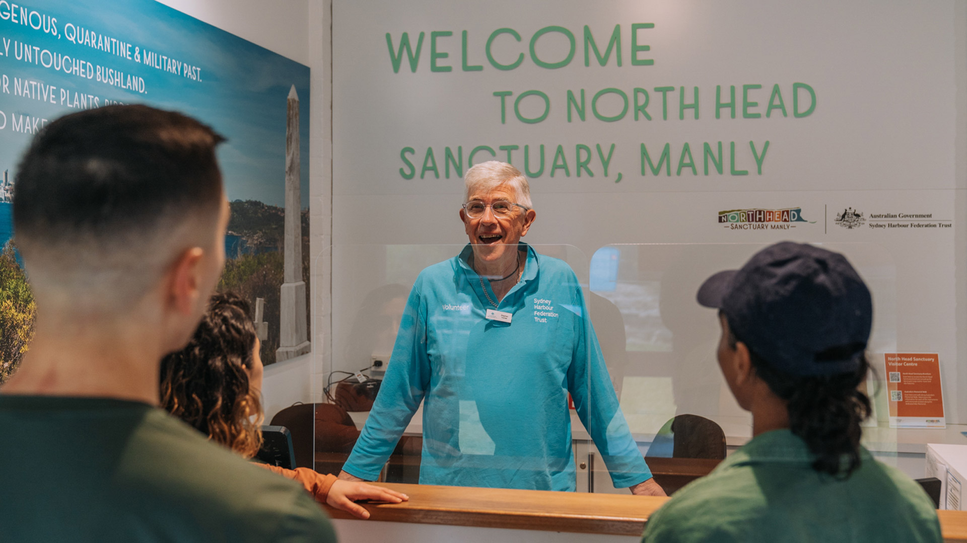 Harbour Trust Volunteer in their blue uniform greeting visitors at the North Head Sanctuary Visitor Centre.